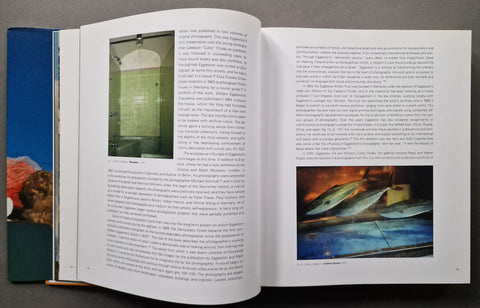 An open book spread showing printed text, two inset photographs, and a larger fish photo on the right page, photographed from above on a dark surface.