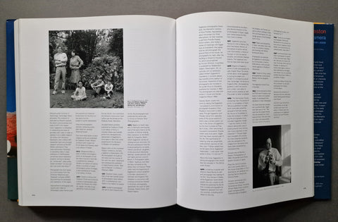 An open book showing two printed pages with columns of text and black-and-white photographs, photographed from above on a dark surface.