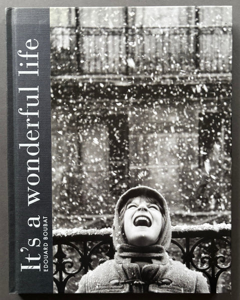 Book titled 'It's A Wonderful Life' by Edouard Boubat with a black and white featuring the image of a female looking up at falling snow.
