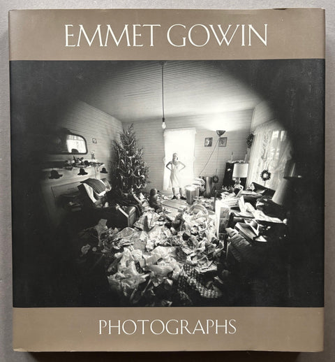 Book titled 'Photographs' by Emmet Gowin with a brown cover featuring the image of a woman in a room with a Christmas tree surrounded by gifts and wrapping paper.