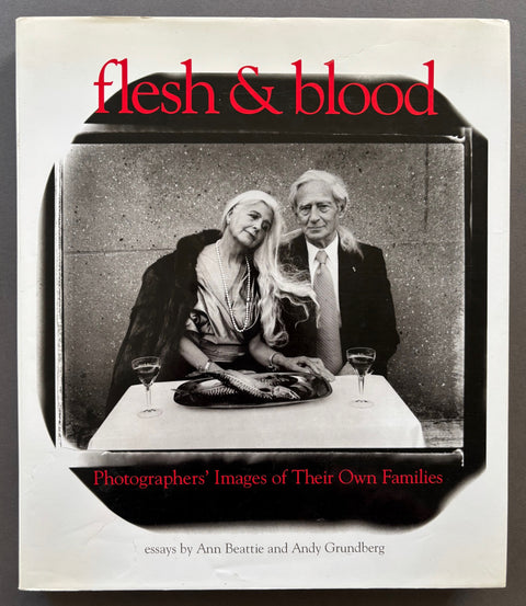 Book titled 'Flesh & Blood: Photographers' Images of Their Own Families' With a cover featuring the image of a man and woman sitting at a table with a plate of fish and 2 glasses of wine.