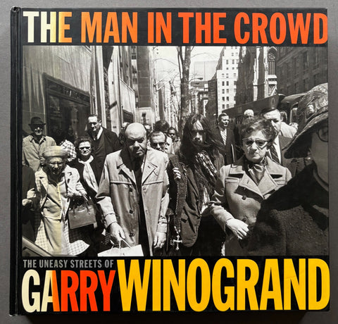 Book titled 'the Man In The Crowd' by Garry Winogrand with a black cover featuring a photograph of a busy New York street.