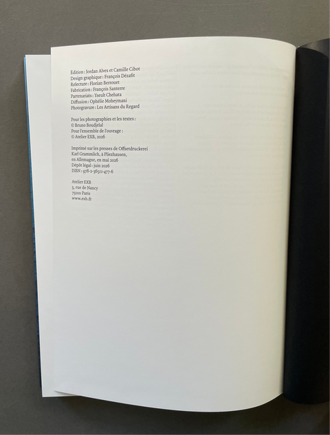 An open book showing the printed interior page with French text, photographed against a dark gray background.