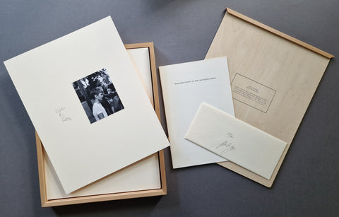 The contents of Hey Fuckface by John Gossage - showing the wooden frame and its back panel as well as one of the 18 mounts with an original silver gelatin print and the words "dickles pig fucker" written in pencil next to it. There is also a small booklet as well as a hand-numbered and signed envelop.