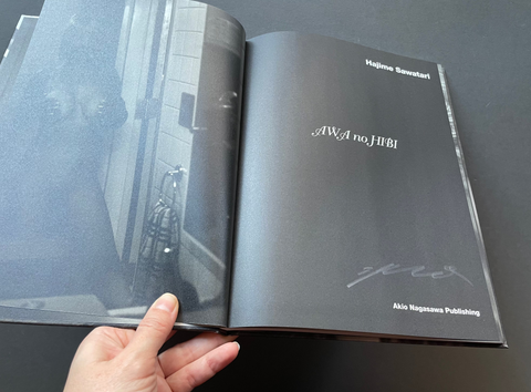 Open book with a black cover displaying text, held by a hand against a dark background.