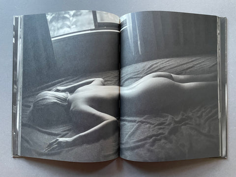 Open book showing a black and white photograph of a person lying on a bed.