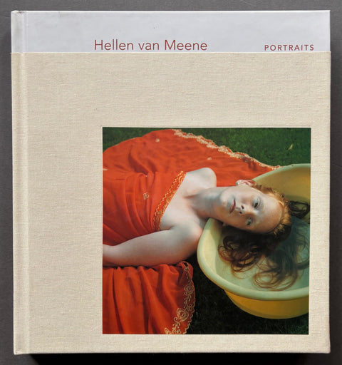 Book titled 'Portraits' by Hellen van Meene with a white and beige cover featuring the image of a girl lying on the ground with her hair in a bowl of water.