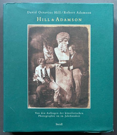 Book titled 'Von den Anfängen der künstlerischen Photographie im 19. Jahrhundert' by David Octavius Hill and Robert Adamson with a blue cover featuring an image of the artists.
