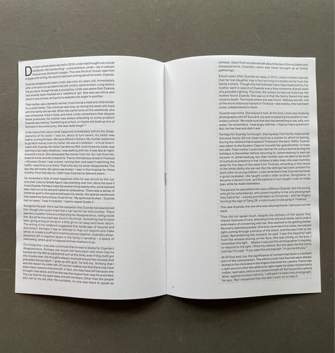 An open book or booklet laid flat on a dark gray surface, showing two white pages filled with black text. The left page has a large letter 'D' at the top, suggesting the start of a chapter or article.