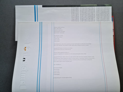 A close-up of printed technical sheets or a booklet with dense text, blue and red vertical lines, and a large vertical wordmark reading 'Tensile.