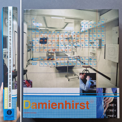 Damien Hirst art book featuring a medical laboratory scene with a periodic table overlay and the title 'Damienhirst' in orange text at the bottom.