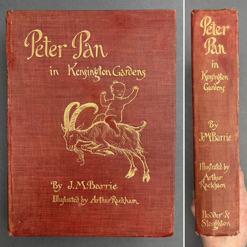 Book titled ''Peter pan in Kensington Gardens' by J. M. Barrie with a red cover and the image of a boy riding a goat all in gold type.