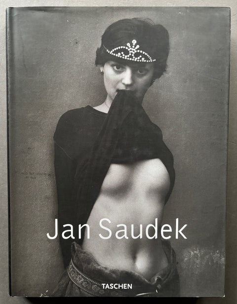 Book titled 'Jan Saudek' with a cover featuring the black and white image of a woman wearing a tiara and holding the hem of her top in her teeth.
