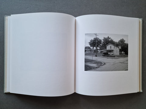 An open book, showing a black-and-white photograph of a house and street scene printed on the right page.