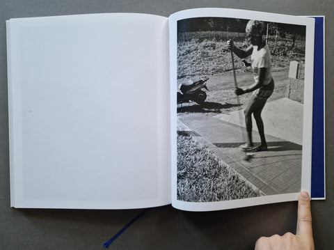 An open book, showing a black-and-white printed photograph of a person outdoors on the right page and a blank white left page.
