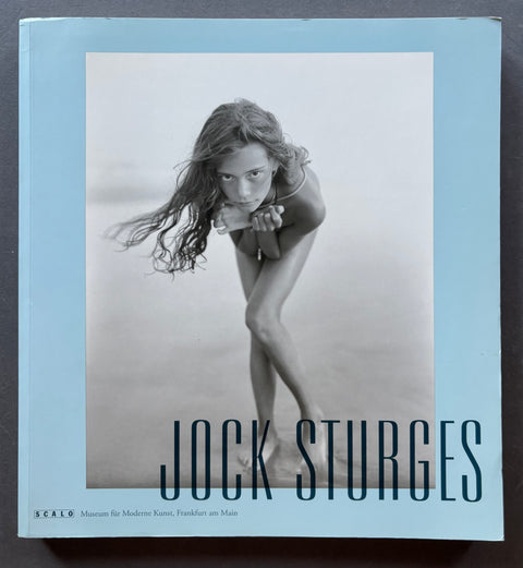 A hardcover art book titled 'Jock Sturges' by Sealo, featuring a large black and white photograph of a woman on the front cover against a light blue border.