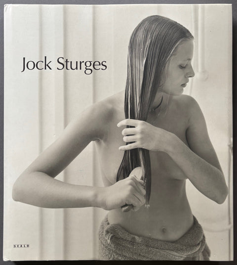 Book titled 'New Work 1996-2000' by Jock Sturges with a white cover featuring a photograph of a semi-naked woman brushing her wet hair.