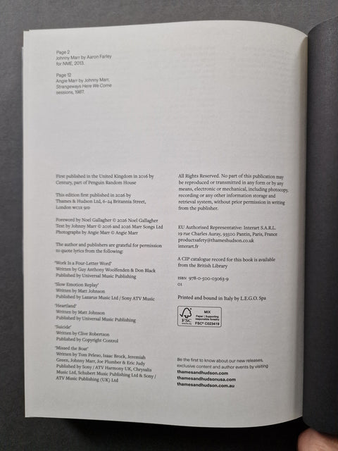 A close-up of an open book  showing printed text on white pages, photographed against a dark gray surface. 