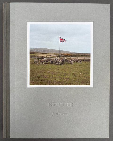 Book titled 'Empire' by Jon Tonks with a grey cover featuring a tipped in image of a heard of sheep surrounding a Union flag.