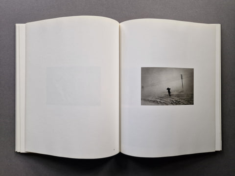 An open book spread showing a photo of a man going through a storm on the right.