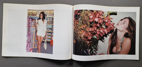 An open book showing to colour photographs of supermodel Stephanie Seymour. In the one on the left she is in a supermarket, the right one is her smelling a bouquet of flowers.