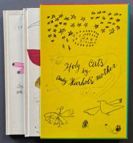 Books titled '25 Cats Name Sam and One Blue Pussy' and 'Holy Cats by Andy Warhol's Mother' with a red and yellow cover featuring drawings of cats, birds, flowers and stars.