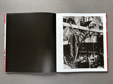 Open book showing a black and white photograph of industrial machinery on a gray background