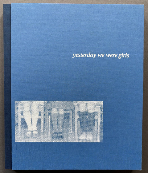 Book titled 'Yesterday We Were Girls' by Katie Prock with a blue cover featuring an image of the legs of 3 girls sitting on chairs.