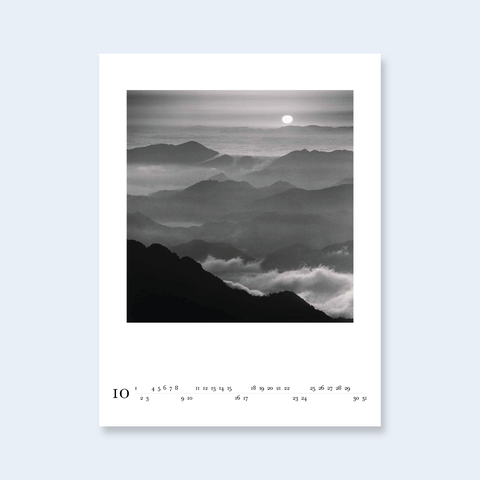 A minimalist calendar page featuring a misty mountain landscape with a sun over the horizon.