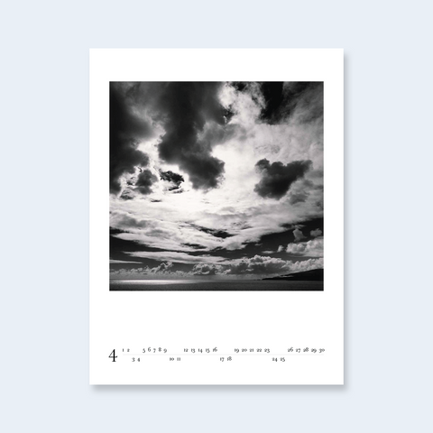 A minimalist calendar page featuring a dramatic cloudy sky photograph.