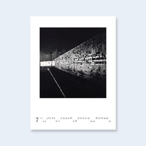 A minimalist calendar page featuring a photograph of a brick wall at night.