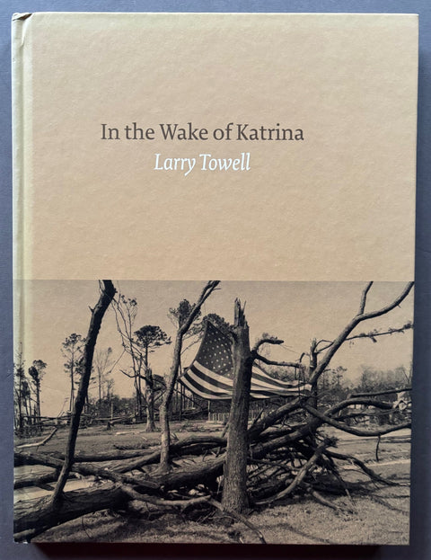 Book titled 'In The Wake of Katrina' by Larry Towell with a beige cover featuring decimated trees holding up a stars and strips flag.