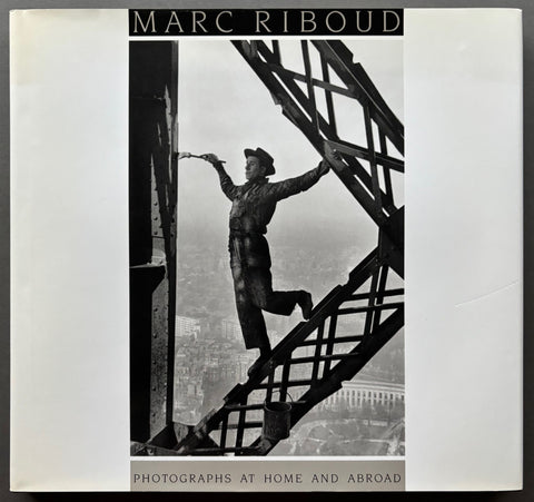 Boo titled 'Photographs at Home and Abroad' by Marc Riboud with a white cover featuring a black and white image of a man painting a very high metal structure.