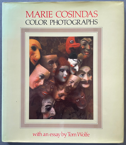 The book cover of 'Marie Cosindas Color Photographs' with an essay by Tom Wolfe, featuring a cream-colored background and a central collage of surreal faces, photographed on a blue surface.