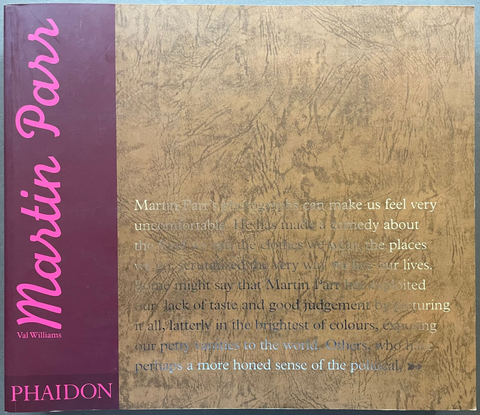 A hardcover book titled 'Martin Parr' by Phaidon, featuring a deep magenta spine and a textured brown cover with white text, photographed on a gray surface.