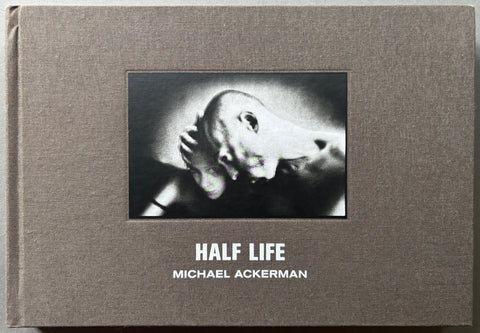 Book titled 'Half life' by Michael Ackerman with a grey cloth cover featuring a photograph of a man and woman.