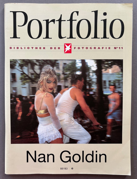 Book titled 'Portfolio No 11' by Nan Goldin' with a white cover featuring the image of 2 people on a bicycle'