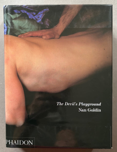 Book titled 'The Devil's Playground' by Nan Goldin with a cover featuring the image of a naked man's torso.