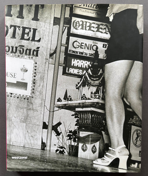 Book titled Patpong: Bangkok's Twilight Zone' by Nick Nostitz with a cover featuring the black and white image of a woman, from the waist down, walking past a Thai shrine on a Bangkok street.