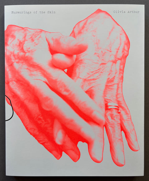 Book titled 'Murmurings of the Skin' by Olivia Arthur with a white cover featuring an image of a pair of hands.
