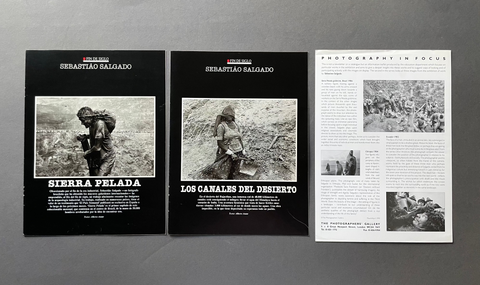 A set of three printed publication pages laid out on a gray surface, including two black covers with black-and-white documentary photos and one white page with text and images under the title 'Photography in Focus'.