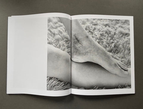 Open book showing a black and white photograph of a foot on grass
