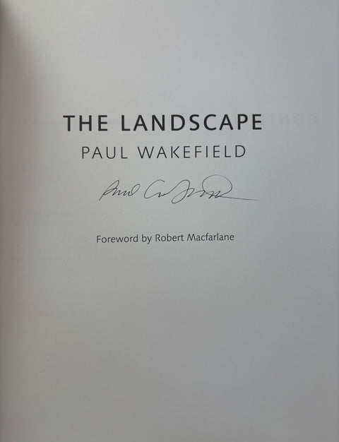 A close-up of a book cover or printed page with the title 'THE LANDSCAPE' and author name 'PAUL WAKEFIELD' in black serif text, plus a handwritten signature and foreword credit.