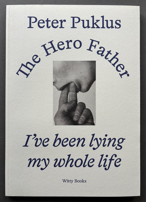 Book titled 'The Hero Father: I've Been Lying My Whole Life' by Peter Puklus with a white cover and blue type featuring the image of a mouth with 2 fingers inserted.