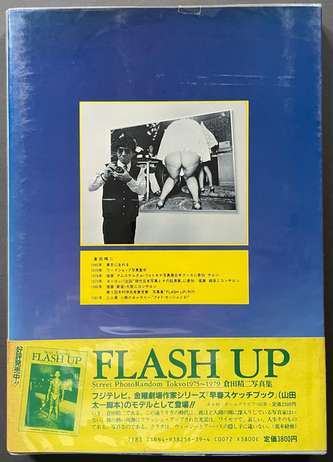 A vintage Japanese Flash Up camera magazine or booklet with a blue cover, yellow lower section, and a central black-and-white photo, photographed against a dark gray background.
