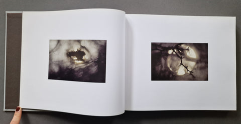An open art book, showing two black-and-white photographic prints on white pages. 