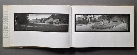 An open book spread showing two black-and-white landscape photographs printed on white pages, photographed against a dark gray background.