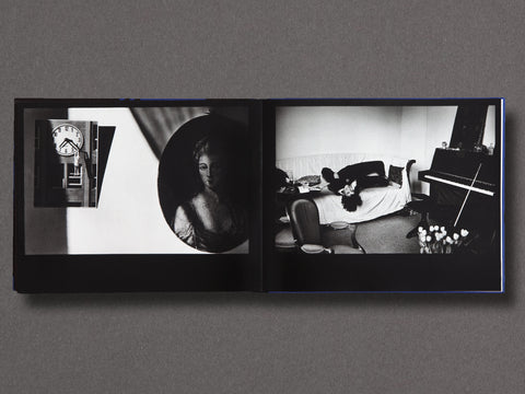 An open black photo book displayed flat against a dark gray background, showing two black-and-white photographic pages with interior room scenes and a circular portrait.
