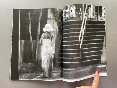 Open book showing black and white photographs of a person in a dress and hat.