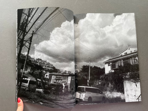 Open book showing a black and white photograph of a street with vehicles and buildings.